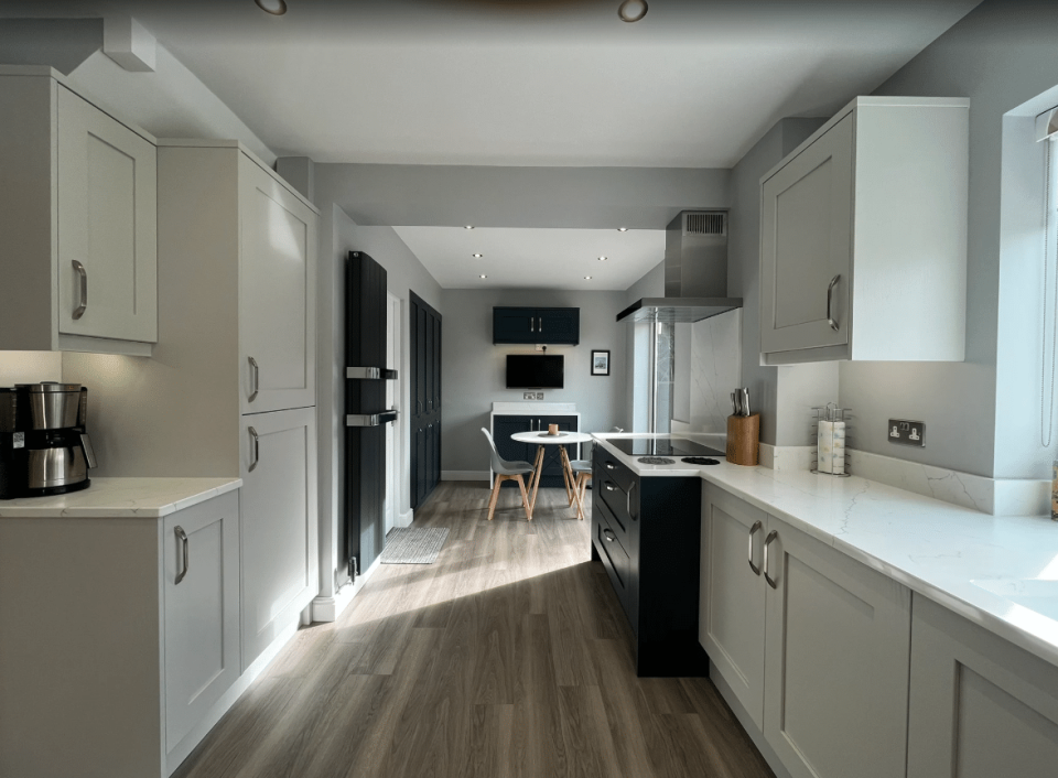 Modern shaker kitchen with light cabinetry, quartz worktops and integrated appliances in a bright open-plan layout designed by Dragonville Interiors.